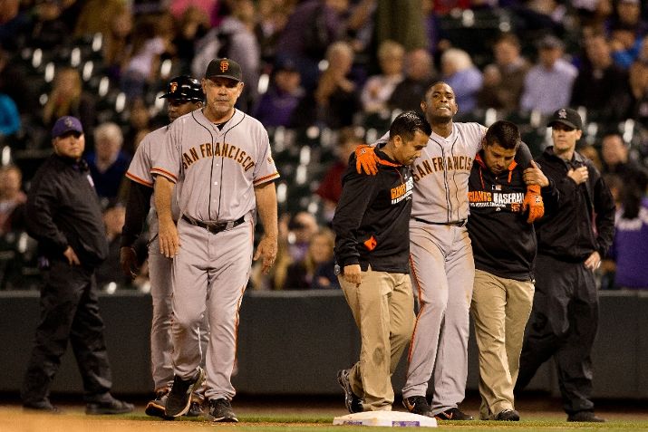 DENVER, CO - MAY 21: Relief pitcher Santiago Casilla #46 of the San Francisco Giants sis helped off the field after injuring his self while tripping over first base as first base coach Hensley Meulens (second from left) and manager Bruce Bochy (third from left) walk off the field during the ninth inning against the Colorado Rockies at Coors Field on May 21, 2014 in Denver, Colorado. The Giants defeated the Rockies 5-1. (Photo by Justin Edmonds/Getty Images)