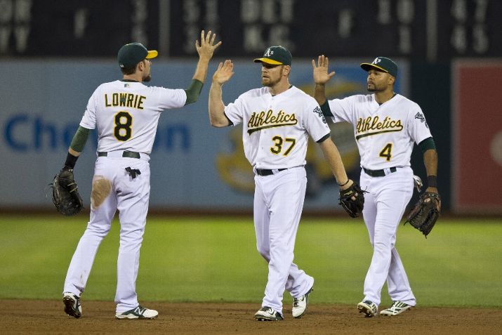 OAKLAND, CA - SEPTEMBER 19: Jed Lowrie #8 of the Oakland Athletics celebrates with Brandon Moss #37 and Coco Crisp after an interleague game against the Philadelphia Phillies at O.co Coliseum on September 19, 2014 in Oakland, California. The Oakland Athletics defeated the Philadelphia Phillies 3-1. (Photo by Jason O. Watson/Getty Images)