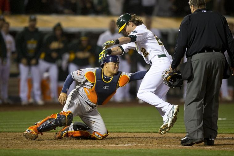Houston Astros catcher Hank Conger, left, tags out Oakland Athletics' Josh Reddick in the tenth inning of a baseball game Friday, April 24, 2015, in Oakland, Calif. (AP Photo/Ben Margot)