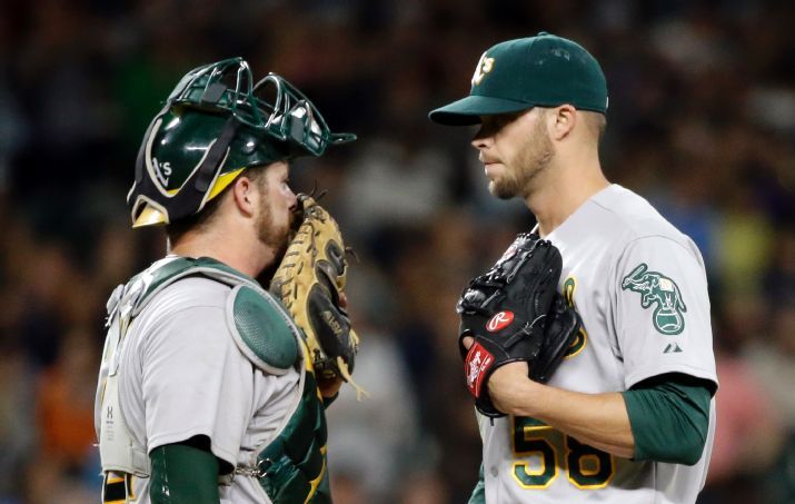 Oakland Athletics catcher Stephen Vogt, left, and relief pitcher Evan Scribner talk on the mound after the Seattle Mariners scored in the seventh inning of a baseball game Friday, May 8, 2015, in Seattle. (AP Photo/Elaine Thompson)